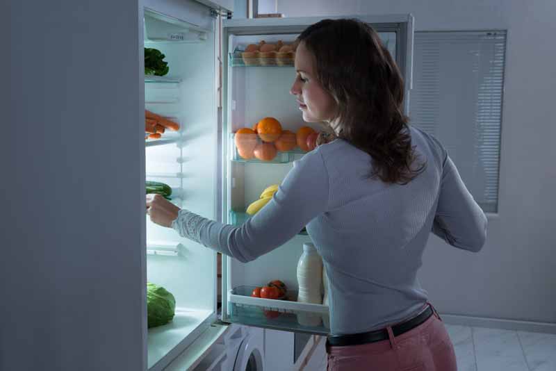 Lady looking for food in the fridge
